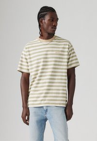 Camiseta de manga corta a rayas en color crema y verde claro, hecha de algodón, con un escote redondo y un pequeño logo de Levi's en el pecho.