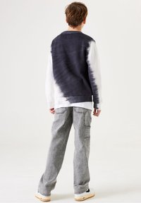 Pullover-Sweatshirt mit einem navy- und weißen Batikmuster, langen Ärmeln und einem runden Ausschnitt. Kombiniert mit grauen Cargo-Hosen.