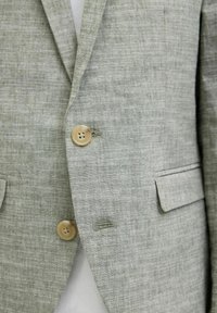 Ljusgrå linnesakko med en texturerad finish, som har två framfickor, två knappar och en skräddarsydd passform.