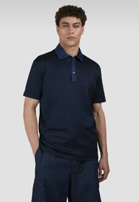 Polo shirt blu navy con colletto a contrasto, maniche corte e patta con tre bottoni. Realizzato in un tessuto morbido e leggero.