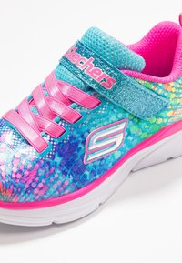 Skechers sneaker met een veelkleurige, gestructureerde bovenkant in blauw, roze en paars, met een glinsterende band en een witte zool.