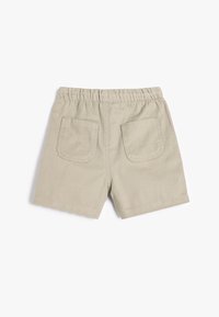 Shorts en coton beige avec une taille élastique, dotés de deux poches arrière et d'une coupe simple et épurée sans embellissements.