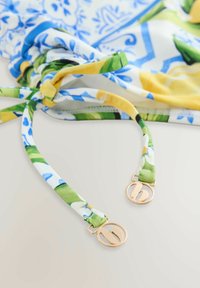 Des sangles en tissu colorées bleu, jaune et vert présentent un motif floral. Des accroches en ton doré accentuent le design. Texture lisse.