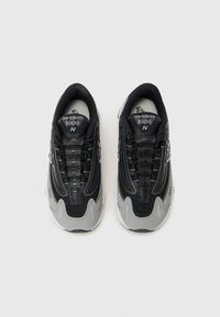 Baskets New Balance noires et grises avec une tige en mesh, des superpositions texturées et une semelle rembourrée. Comprend un système de laçage et des accents de logo.