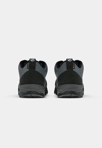 Sapatos de caminhada em preto e cinza com um acabamento texturizado, calcanhar almofadado e solado de borracha. Apresenta uma etiqueta com a marca na parte traseira.