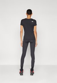 Svart trenings T-skjorte med korte ermer og rund hals, kombinert med svarte leggings. Har små logo aksenter på begge plaggene.