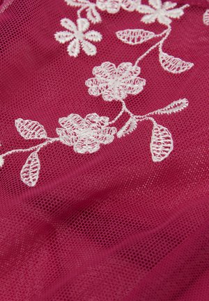 Hvid blomsterbroderi med blade på tynd mørkrosa mesh-stof, der viser delikate tråddetaljer og teksturerede mønstre.