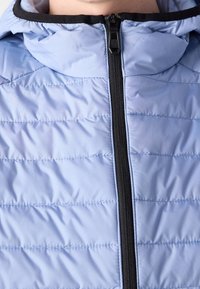 Ljusblå pufferjacka med en åtsittande huva, med horisontella stickade linjer, en svart dragkedja och en slät, glänsande textur.
