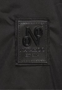 Zwarte stoffen label gestikt op zwart materiaal, met in reliëf "NAVAHOO", een gestileerd logo, en de tekst "EST 2014".