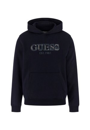 Sweatshirt à capuche bleu marine avec poche avant, arborant un logo "GUESS" bien en vue et du texte "EST.1981" dans des couleurs contrastées. Texture de tissu douce.