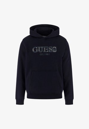 Sudadera con capucha de color azul marino y bolsillo frontal, que presenta un destacado logo de "GUESS" y el texto "EST.1981" en colores contrastantes. Textura de tela suave.