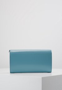 Rektangulär blå läderclutch med en slät yta och subtila sömdetaljer. Dragkedjestängning i ena änden, minimalistisk design.