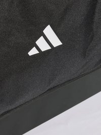 Bolsa de tela negra con superficie texturizada, que presenta un prominente logo blanco de Adidas. La base tiene una textura negra sólida.