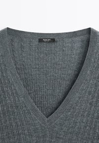 Grau gestrickter V-Ausschnitt-Pullover mit Rippenstruktur und Etikett "Massimo Dutti". Der Stoff wirkt weich und hat ein dezentes, gemustertes Design.