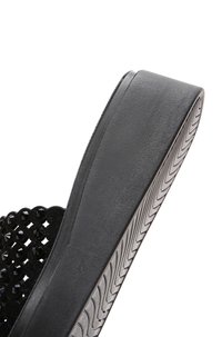 Sandalo slide nero con suola in gomma testurizzata, dotato di una parte superiore decorativa a taglio adornata con accenti neri.