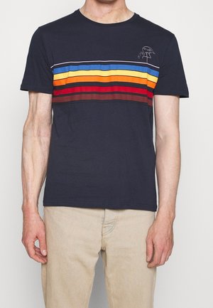 Mann trägt ein dunkelblaues T-Shirt mit horizontalen blauen, gelben, orangefarbenen, roten und braunen Streifen und kleinem Flamingo-Design auf der Brust.