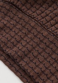 Hnědá pletená látka s texturovaným vzorem čtverců obrysných tmavě modrou barvou. Měkká textura, tkaný design s vystouplými plochami.