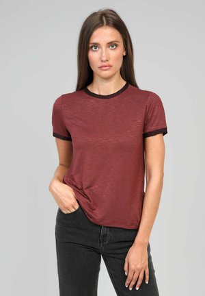 T-shirt marron à manches courtes avec une finition texturée et un col et des bords de manches en rib noir contrastant, associé à un jean foncé.