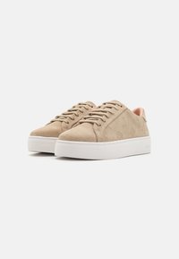 Beige semskinnsneakers med hvite gummisåler, med glatte lisser, subtile logodetaljer og et lavprofilert design.