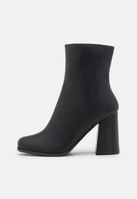 Czarny botek za kostkę o gładkim, matowym wykończeniu, zaokrąglonym nosku i teksturowanym obcasie w kształcie bloku. Elegancki, minimalistyczny design bez widocznych akcentów.