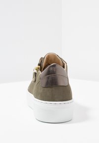 Zielone oliwkowe zamszowe sneakersy z błyszczącym metalicznym akcentem na pięcie i białą gumową podeszwą. Posiadają złote detale po bokach.