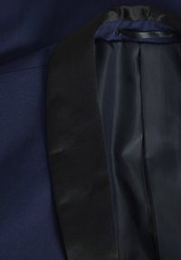 Blazer blu navy con colletto in satin nero e fodera interna; presenta una texture liscia e un design strutturato con revers tradizionale.