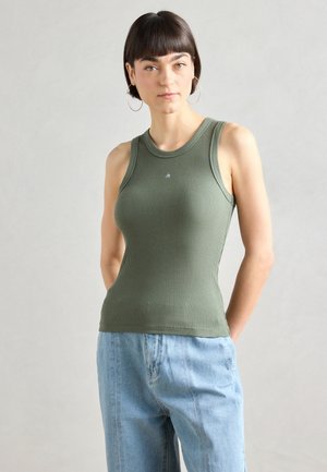 Olivenfarget ermeløs ribbestrikket tanktop med rund hals og lite logo på brystet, kombinert med lyseblå vide jeans.