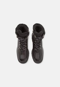 Bottines noires imperméables avec doublure en fausse fourrure, devant à lacets et accents texturés. Conception robuste avec semelles épaisses pour une meilleure adhérence.