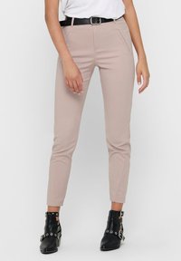 Harmaat istuvat housut, joissa on sileä pinta, etutaskut ja musta vyö. Yhdistetty mustiin nilkkureihin, joissa on hopeanvärisiä yksityiskohtia.