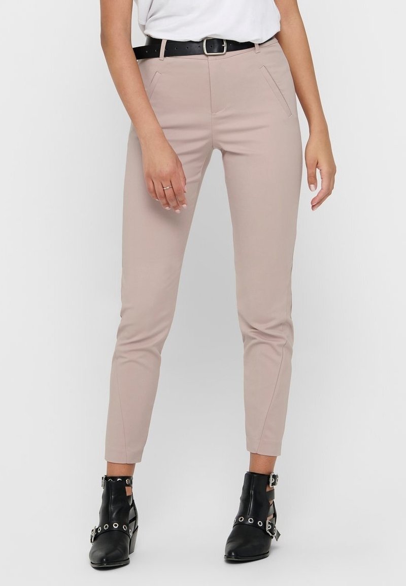 Harmaat istuvat housut, joissa on sileä pinta, etutaskut ja musta vyö. Yhdistetty mustiin nilkkureihin, joissa on hopeanvärisiä yksityiskohtia.