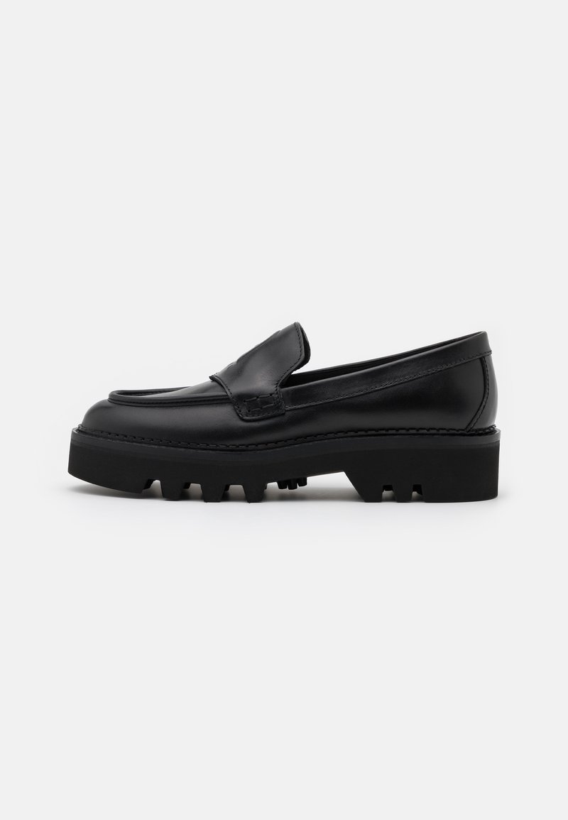 Mocassin en cuir noir avec semelle crantée épaisse et détail de coutures apparentes, présenté en profil latéral sur fond blanc.
