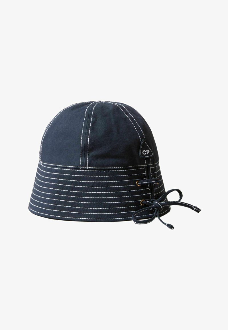 Chapeau seau marine en coton avec des coutures blanches. Il dispose d'un cordon de serrage et d'accents en métal pour l'ajustement. Son design est structuré et arrondi.