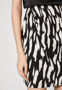 Svart och vit mönstrad kjol med en strukturerad textil. Designen har djärva, oregelbundna streck och en figurnära silhuett.