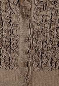 Brązowy dziergany top z wyraźnymi falbankami z przodu, o gładkiej fakturze i zapięciu na guziki.