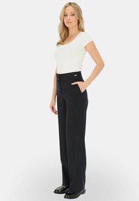 Biały dopasowany top z krótkimi rękawami połączony z granatowymi spodniami w pasy o szerokiej nogawce, z wysokim stanem i bocznymi kieszeniami. Czarne mokasyny.