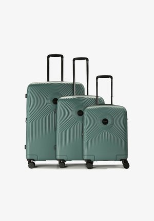 Tre valigie rigide color turchese con motivi a cerchi concentrici, manici telescopici neri e quattro ruote girevoli, disposte per dimensione.