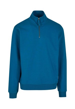 Niebieski pulower z ćwiartkowym zamkiem, wykonany z miękkiej, teksturowanej tkaniny, z długimi rękawami i ściśniętymi mankietami. Posiada metalowy zamek przy szyi.