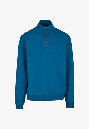 Niebieski pulower z ćwiartkowym zamkiem, wykonany z miękkiej, teksturowanej tkaniny, z długimi rękawami i ściśniętymi mankietami. Posiada metalowy zamek przy szyi.