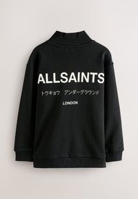 Čierna mikina s vysokým golierom, s veľkým bielym nápisom "ALLSAINTS" a "LONDON" v rôznych jazykoch, vyrobená z mäkkej látky.