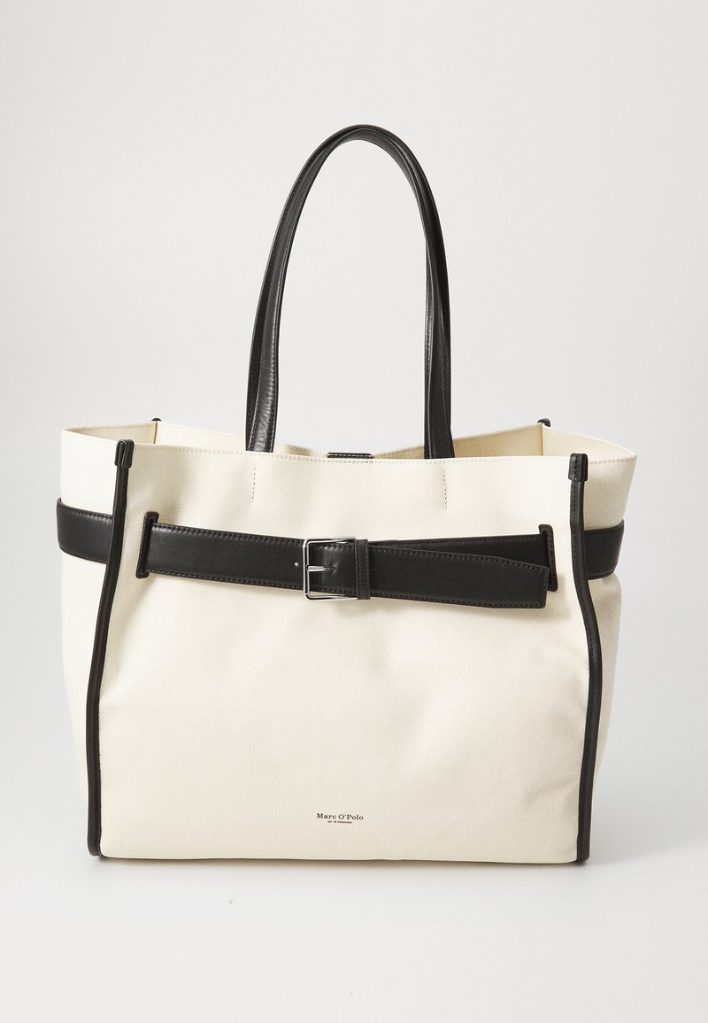 Canvas tote bag in cream with black leather accents, including a belt detail and double handles. Features a structured shape and metal hardware.