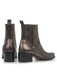 Botines de tobillo metálico bronce con acabado texturizado, tacón bajo y tirador. Presentan costuras sutiles y pequeños herrajes decorativos.