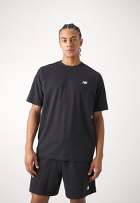 Black cotton t-shirt with short sleeves and a round neckline, featuring a small white logo on the left chest. Paired with matching shorts.