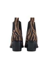 Botines tobilleros a rayas de cebra en marrón y negro, con tacón bajo de bloque y paneles elásticos en los laterales para facilitar el calzado.