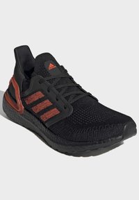 Basket noir avec une tige en tricot texturé, des rayures rouges en accent et une semelle rembourrée. Comprend un contrefort de talon pour un soutien.