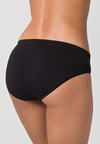 Černé bikiny s hladkou texturou, nízkým střihem a minimálním pokrytím. Jednoduchý design bez vzorů nebo ozdob.