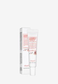 Tubo blanco con tapa abatible etiquetado "Crema para manchas Centella Adiós enrojecimiento". La caja presenta texto rojo y un gráfico de personaje de caricatura. Tamaño de 15g.