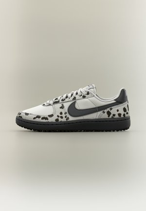 Biało-czarny sneaker Nike z akcentami w wzór krowi, czarne logo Swoosh, czarna podeszwa i białe sznurowadła, pokazany z boku na jednolitym tle.
