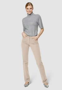 Beige corduroy broek met een slim-fit ontwerp, gecombineerd met een lichtgrijze korte mouw turtleneck trui. Satijnen zilveren flats.