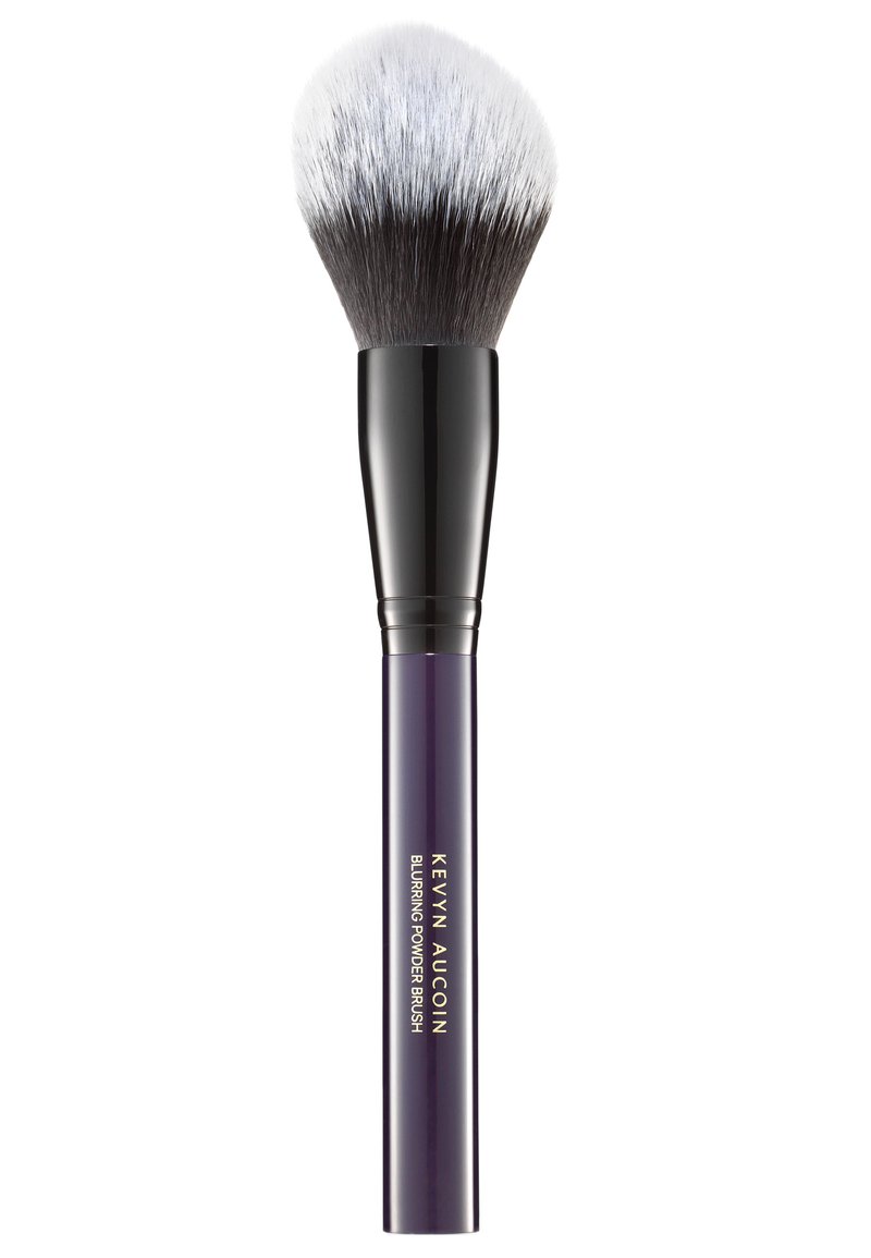 Runde Kabuki-Schminkbürste mit einem zweifarbigen Kopf aus schwarzen und silbernen Borsten sowie einem eleganten lila Griff mit goldenem Text für Marken- und Produktnamen.