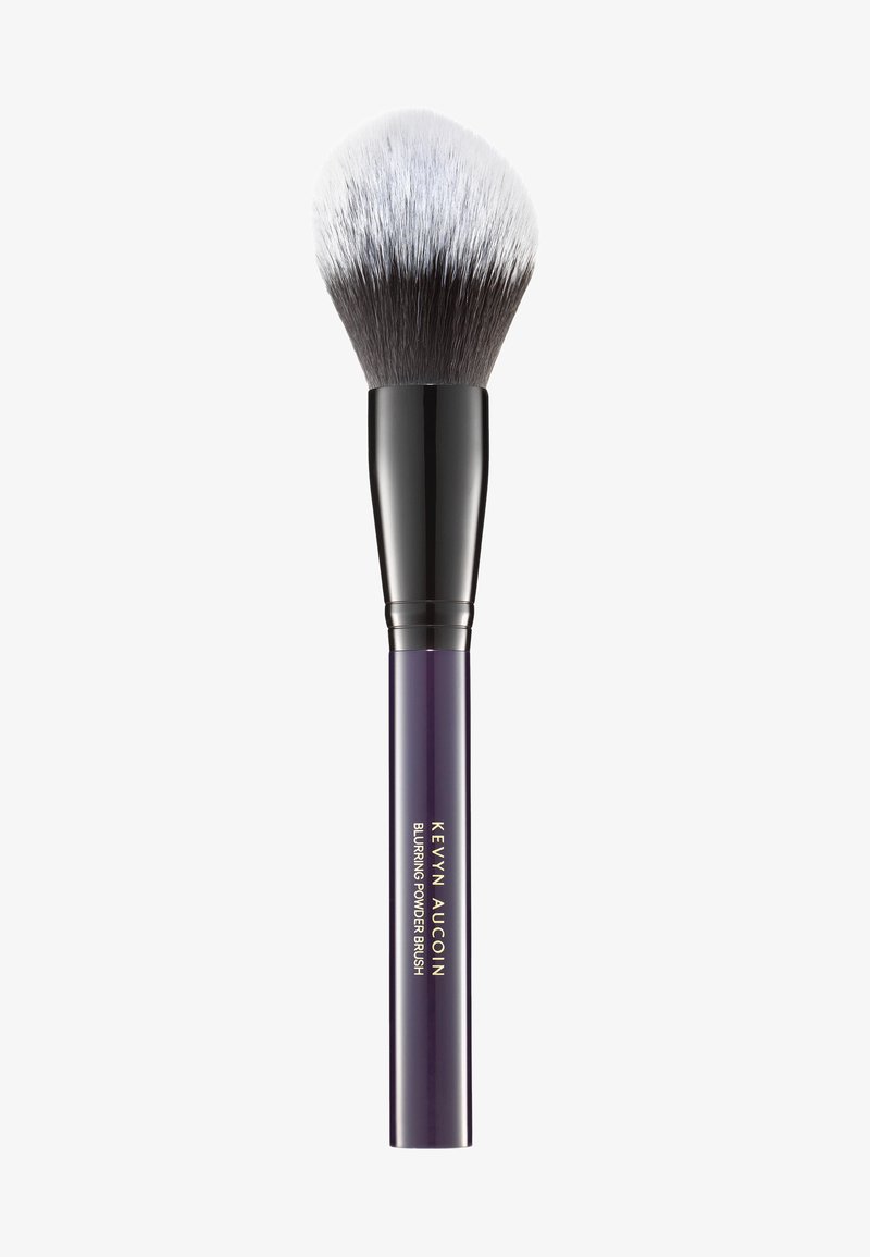 Runde Kabuki-Schminkbürste mit einem zweifarbigen Kopf aus schwarzen und silbernen Borsten sowie einem eleganten lila Griff mit goldenem Text für Marken- und Produktnamen.